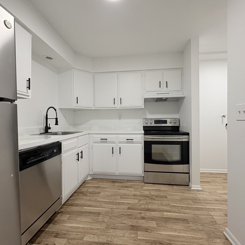 Renovated kitchen with white cabinets, dishwasher, and new flooring